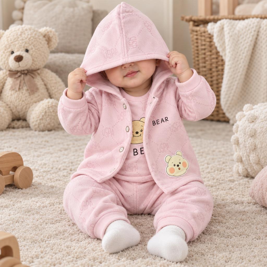 Baby wearing a soft Pink three-piece winter suit with a bear-applique hooded jacket and matching cuffed trousers.