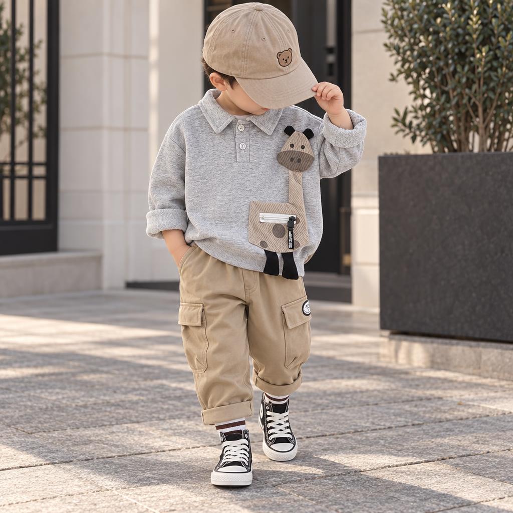 Little boy wearing the Grey horse applique collared shirt with Beige cuffed cargo pants, styled outdoors with a cap and sneakers.