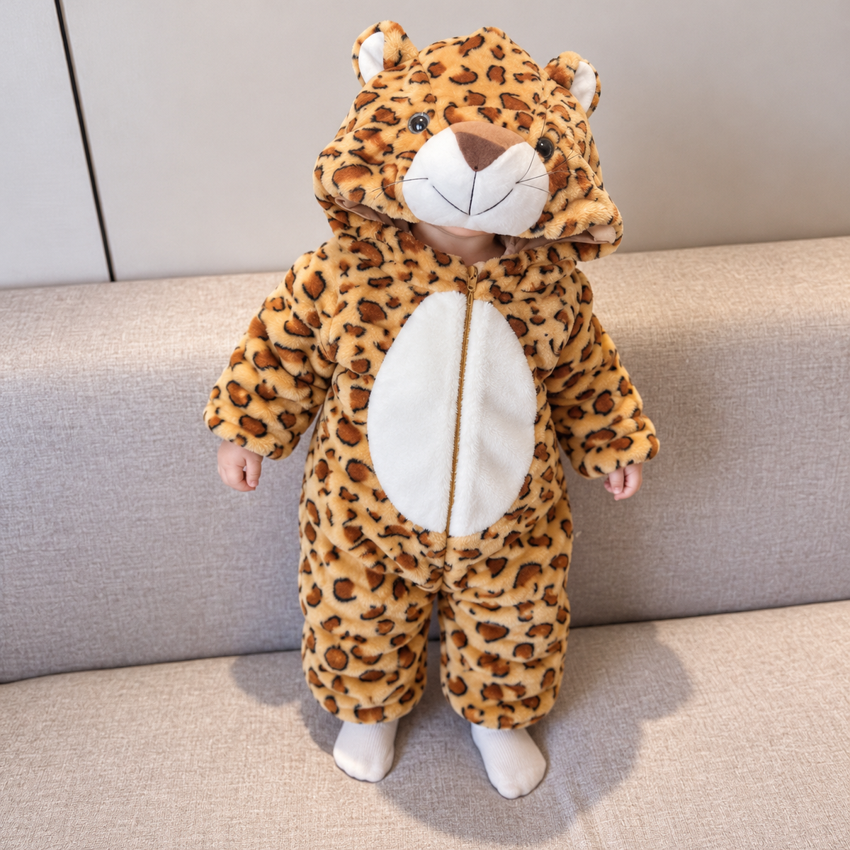 Baby wearing the Brown leopard-print plush hooded romper, featuring rounded ears, a raised leopard face hood, White tummy panel and full front zip.