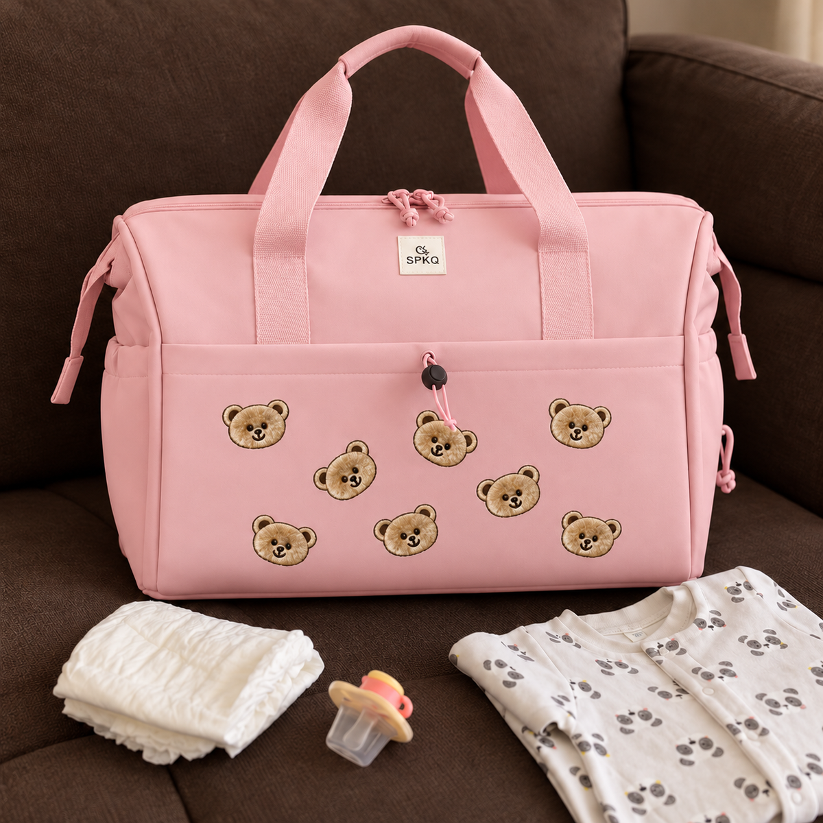 Pink teddy bear easy carry mommy bag displayed on a sofa with wide handles, front zip pocket and baby essentials