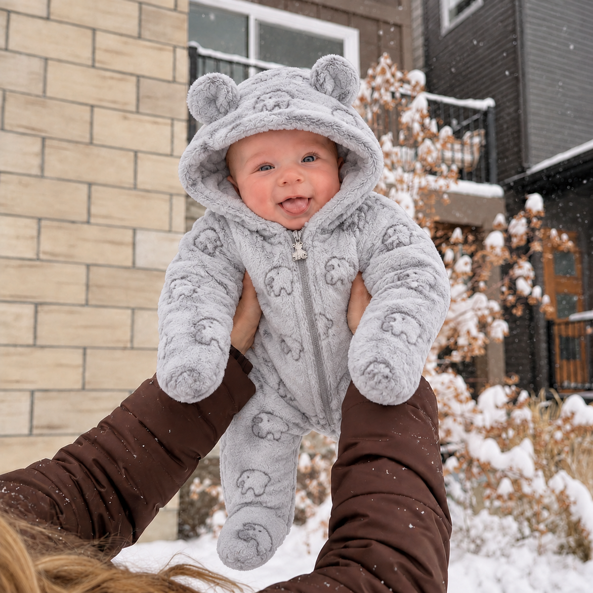 Baby wearing the grey animal-print shaggy hooded romper outdoors in snow, showing the plush texture, rounded bear ears and full front zip.