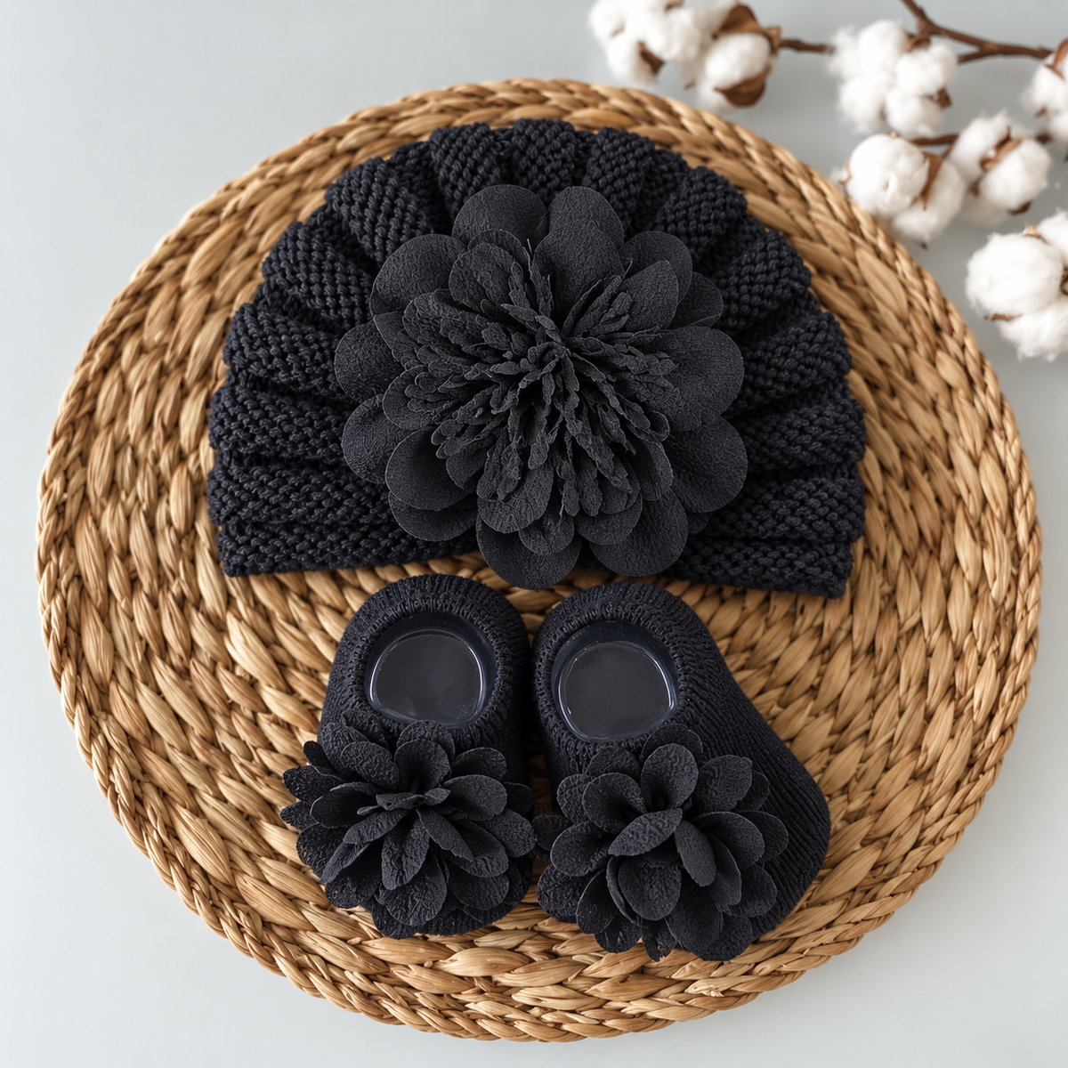 Black baby flower turban cap with matching Black socks, styled on a woven mat and finished with layered Black fabric blooms.