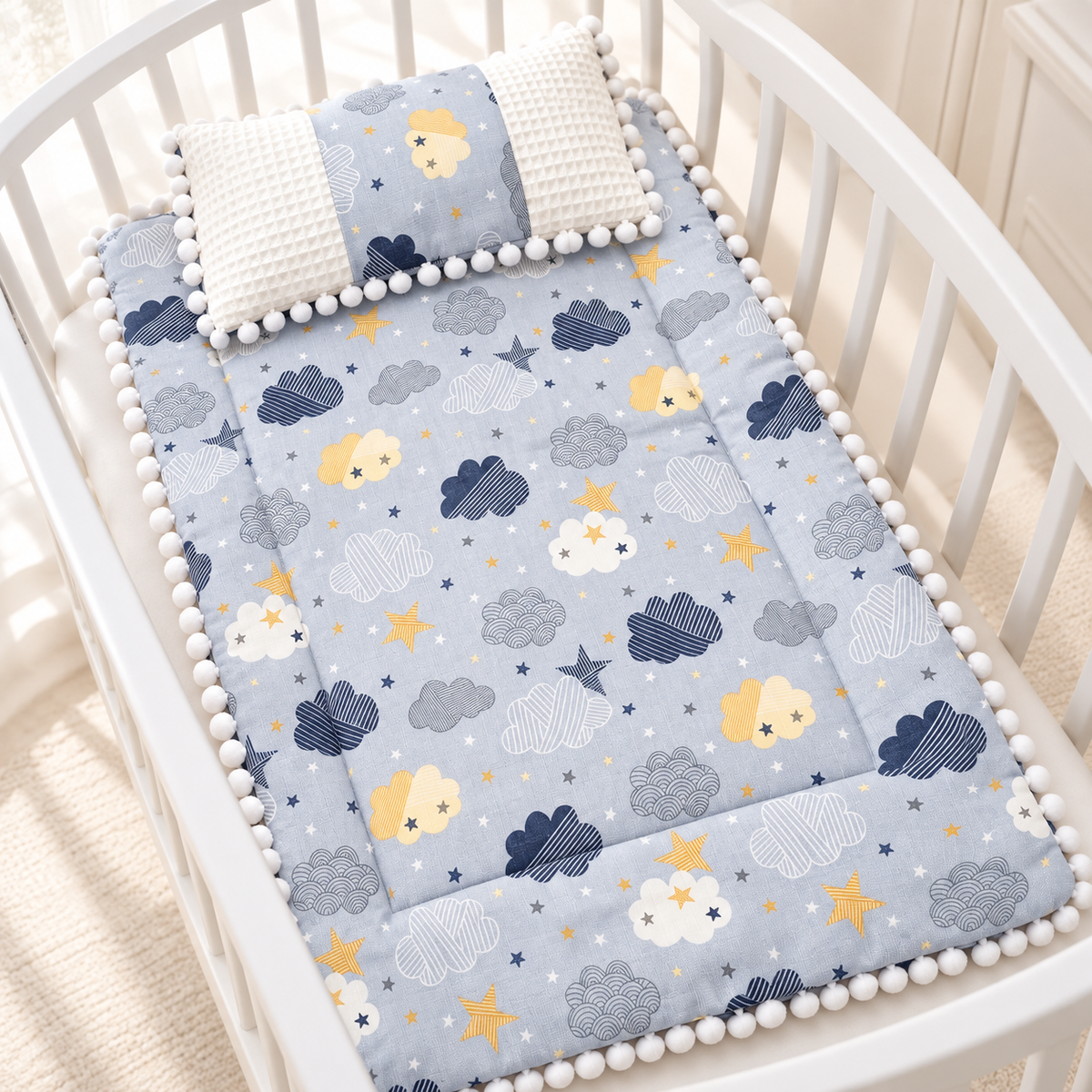 Royal Blue cloud and star printed baby sleeping sheet with matching White waffle-textured pillow, displayed inside a White crib.