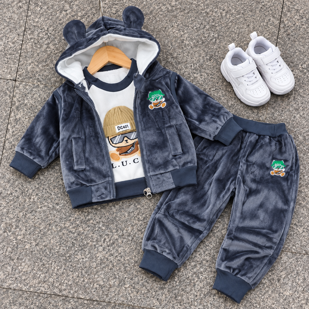 Grey kids velvet 3-piece suit displayed on a grey floor, featuring a rounded bear-ear hood and sunglasses character graphic shirt.