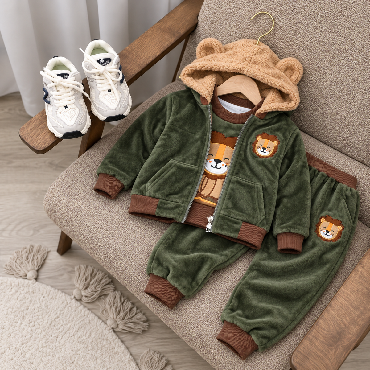 Dark Olive Green kids 3-piece velvet suit displayed on a chair, showing the teddy-ear hooded jacket with plush-look hood lining, bear graphic shirt and matching cuffed trousers.