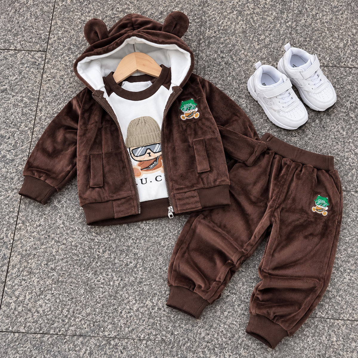 Dark Brown kids velvet 3-piece suit flat lay showing the bear-ear hood, zip-front pocket jacket and matching character-patch trousers.