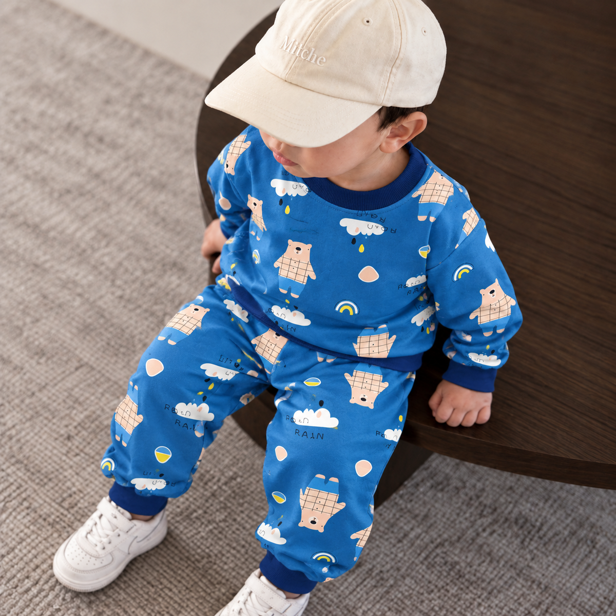 Toddler boy wearing the bright blue bear and cloud print shirt and trouser set with navy blue ribbed trims.