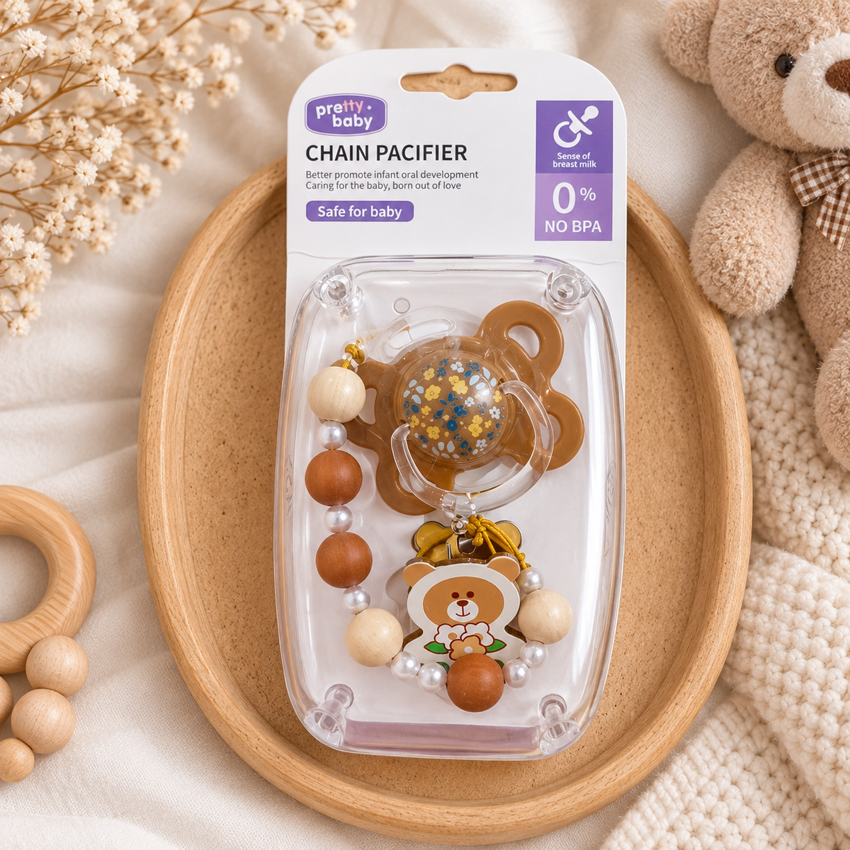 Brown bear floral pacifier with matching bead chain displayed in clear Pretty Baby chain pacifier retail packaging on a wooden tray.