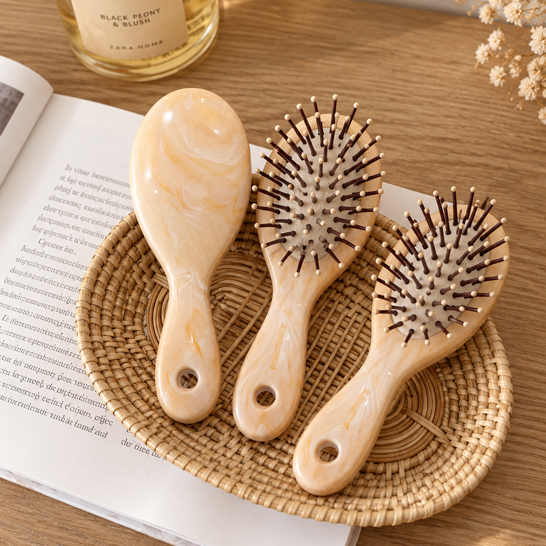 Three mini marble-look hair brushes in Cream and Beige tones, displayed on a woven tray with dark Brown rounded-tip pins and hanging-hole handles.