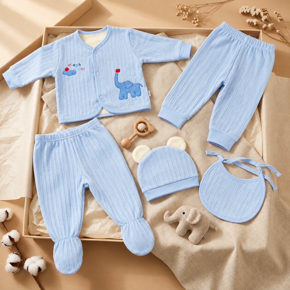 Pastel Blue ribbed velvet baby 5-piece starter set flat lay with elephant-applique button-front top, two trousers, ear cap and tie bib.