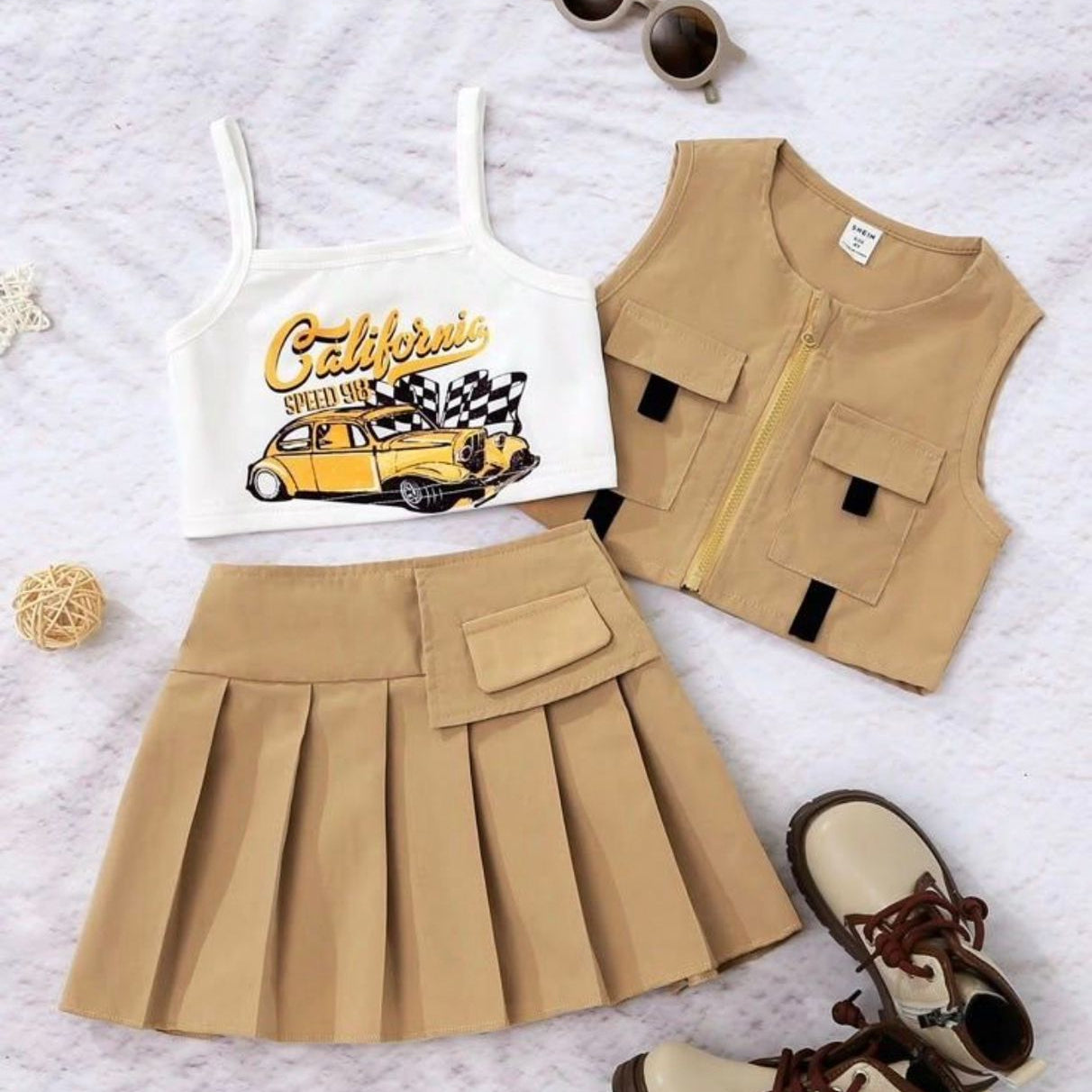Children's outfit with tank top, skirt, vest, and boots on a light background