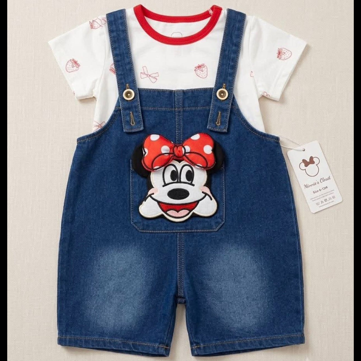 Children's outfit with denim overalls featuring a cartoon character on a beige background