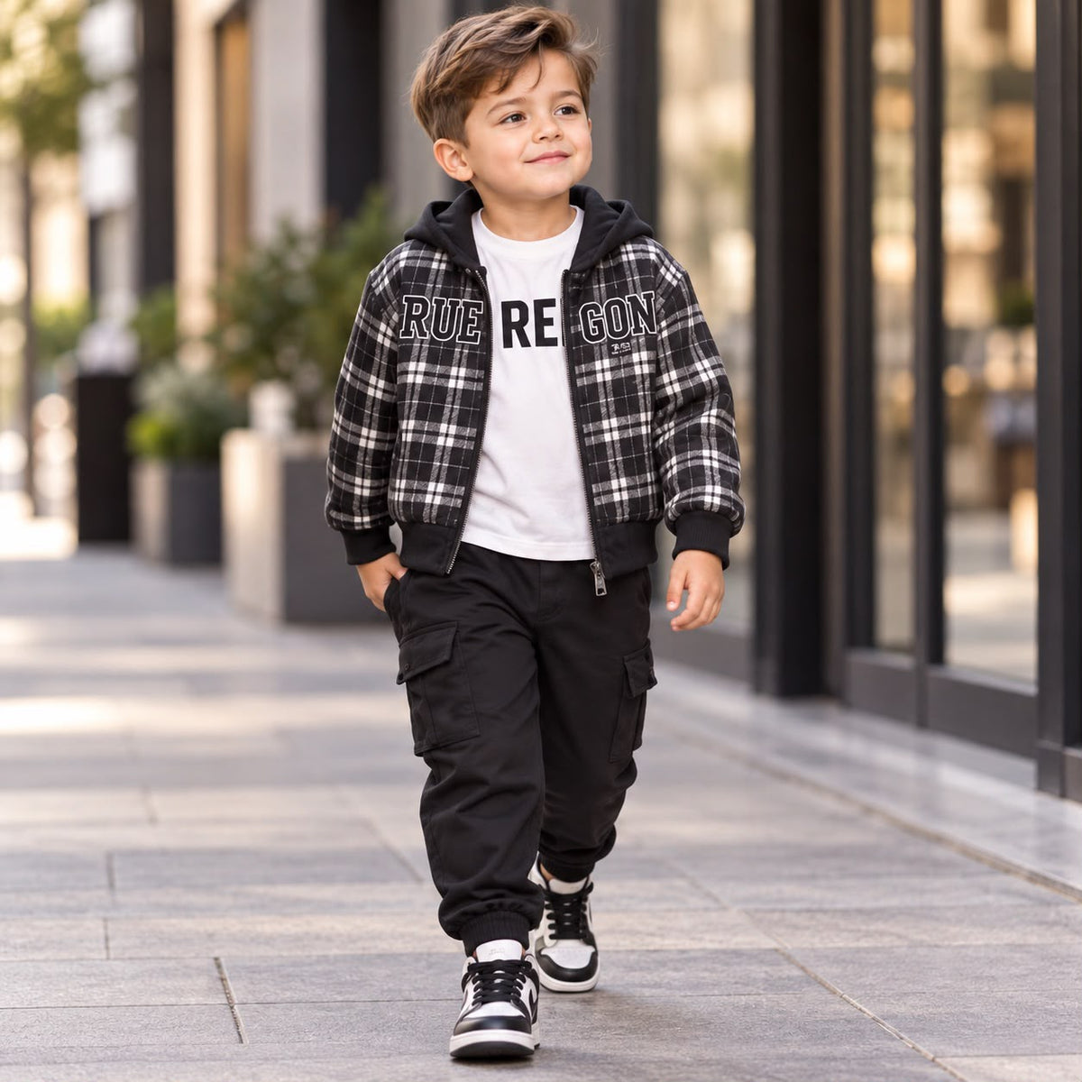 Boy modelling the Black and White checked hooded zip jacket, White graphic inner shirt and Black cuffed cargo trousers.