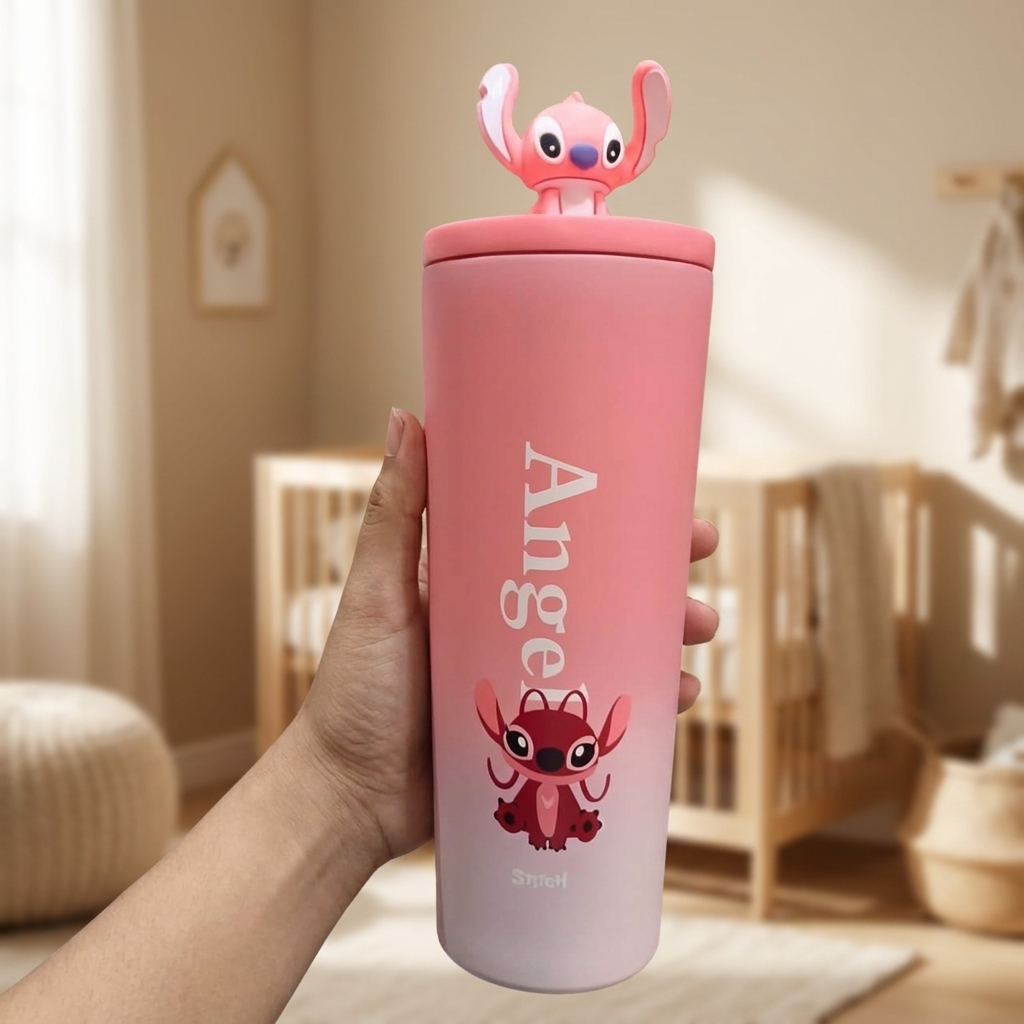 Pink Angel Stitch character tumbler held in hand in a nursery setting, showing the vertical Angel print, front character artwork and pink 3D lid figure.